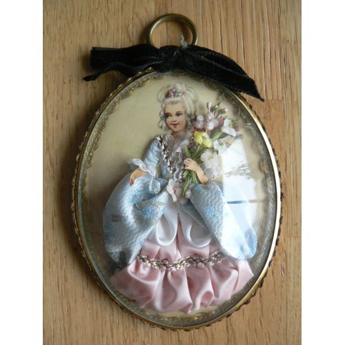 Miniature Ovale, Sous Globe En Plastique Et Sur Carton, Avec Encadrement En Métal Doré Recouvert D'un Petit Galon Doré. Représentation D'une Femme Dans Une Robe Ancienne Et Tenant Un Bouquet De Fleurs