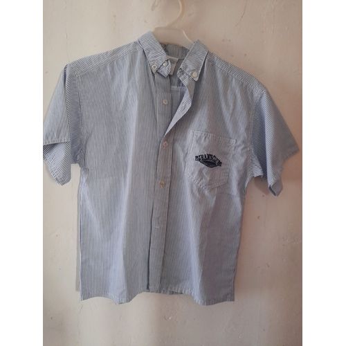 Chemise Rayée Manches Courtes. Taille 10 Ans. Marque Jeans Club. Poche Avant Siglée. 100 % Coton. Nota : Chemise Neuve Mais Dernier Bouton Du Bas Cassé.