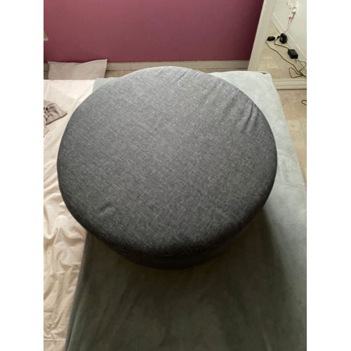 Pouf Menzzo. Coloris Tissu Gris Fonc, Le Pouf Est Muni DUn Pied Central Dor Avec Une Assise Rembourr Pour Plus De Confort, Et Un Revtement En Tissu Doux.