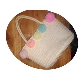 Sac à mains en paille de papier tressée. Modèle avec poignées sur le dessus et pompons décoratifs aux couleurs pastel. Doublure 100% polyester. Dimensions approximatives : 7*17*26 cm.