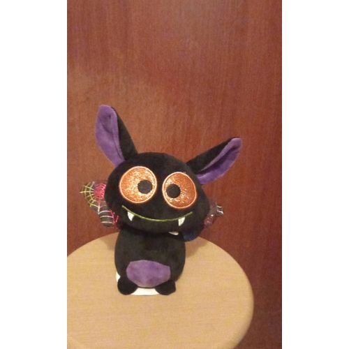 Peluche chauve-souris vampire OFFIZY, coloris noir et multicolore, yeux oranges scintillants, intérieur oreilles mauves, ailes imprimées toiles d'araignées jaunes,roses et argentées scintillantes.