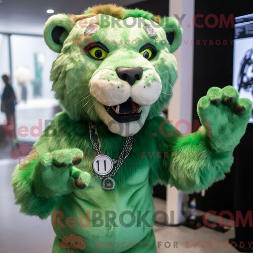 Costume Mascotte Redbrokoly De Smilodon Vert Habillé D Un T-Shirt Graphique Et De Boucles D Oreilles