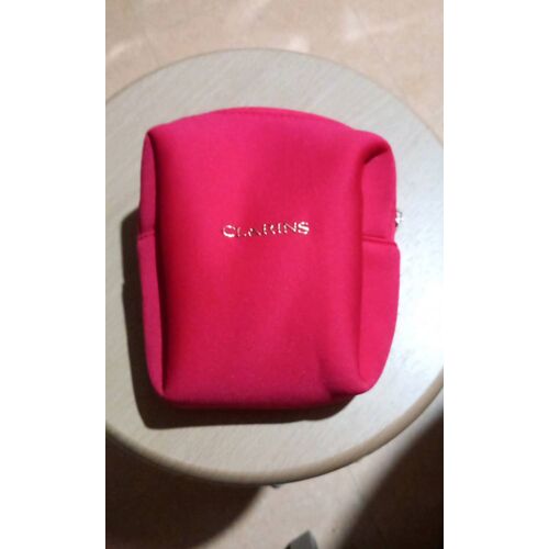 Pochette unique zippée Clarins,coloris rouge, 100% polyester ( 93% matière recyclée ),Clarins en métal doré collé sur l'avant, tirette zippe gravée logo marque, doublée, H 18, l 16, E 10 cm.